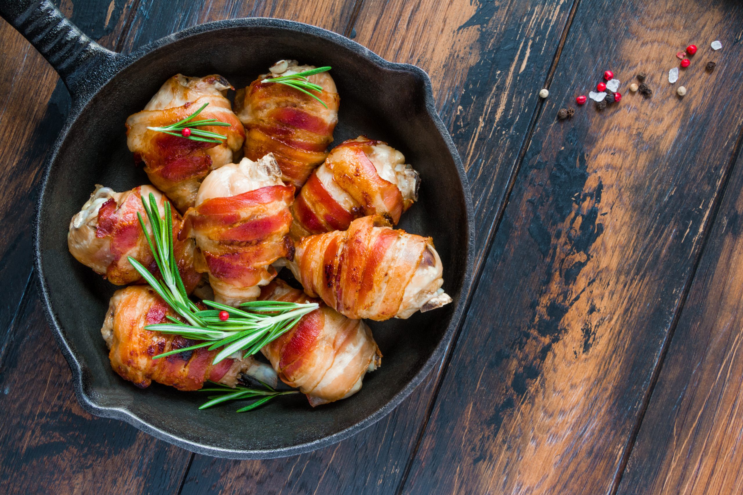Bacon,Wrapped,Chicken,Drumsticks,In,A,Black,Cast-iron,Skillet,On